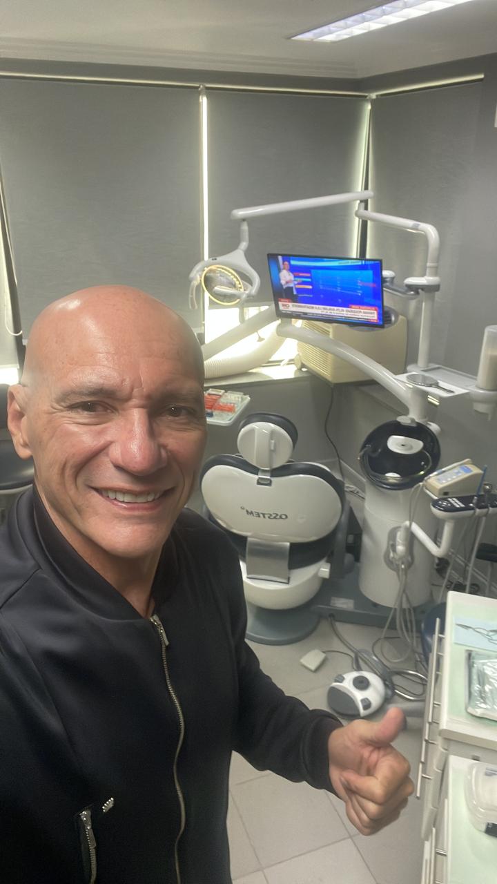 Dr. Ricardo Pina no consultório odontológico do Itaim Bibi, com cadeira e equipamentos ao fundo